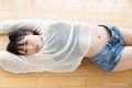 Lying on her back arms raised wearing shorts